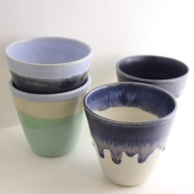 Douceur d'émail Quatre pots en céramique dans des teintes pastel, empilés.