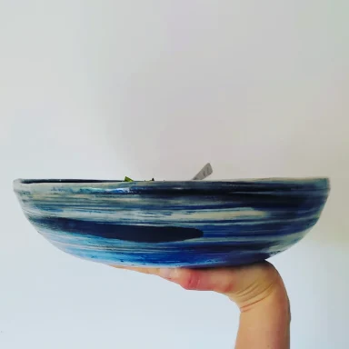 Couscous en famille Bol aux nuances de bleu, porté à la main, avec une surface lisse et arrondie.